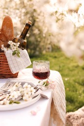 Stylish table setting with beautiful spring flowers and wine in garden