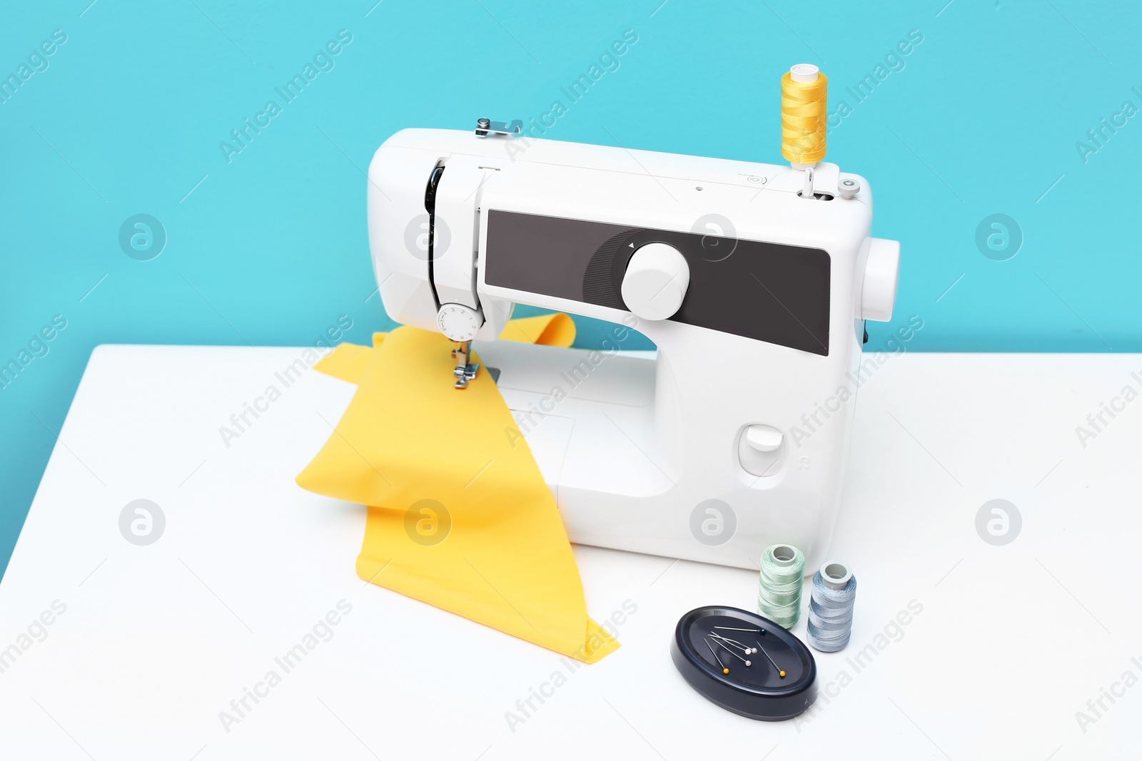 Photo of Modern sewing machine on table against color background