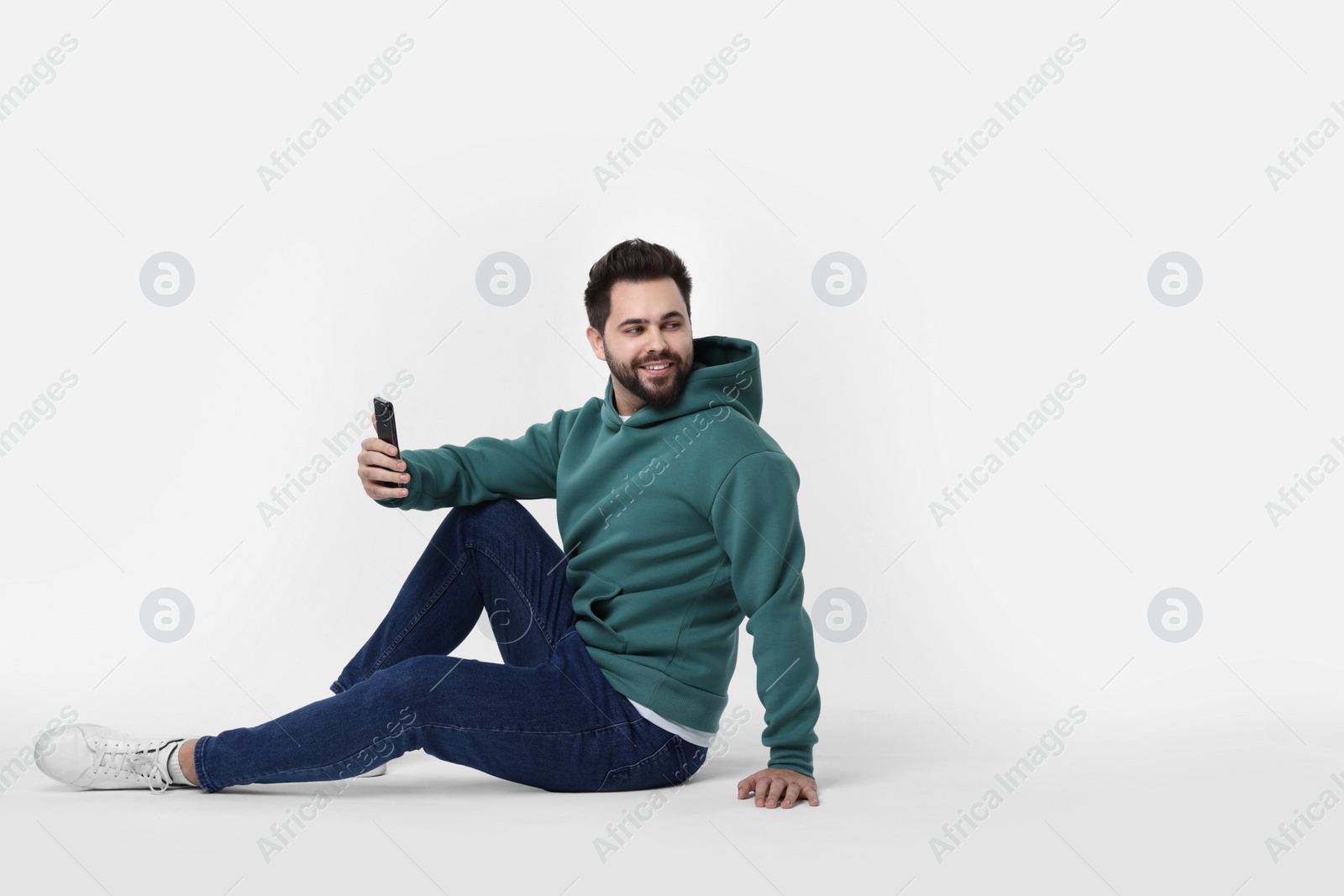 Photo of Happy young man using smartphone on white background