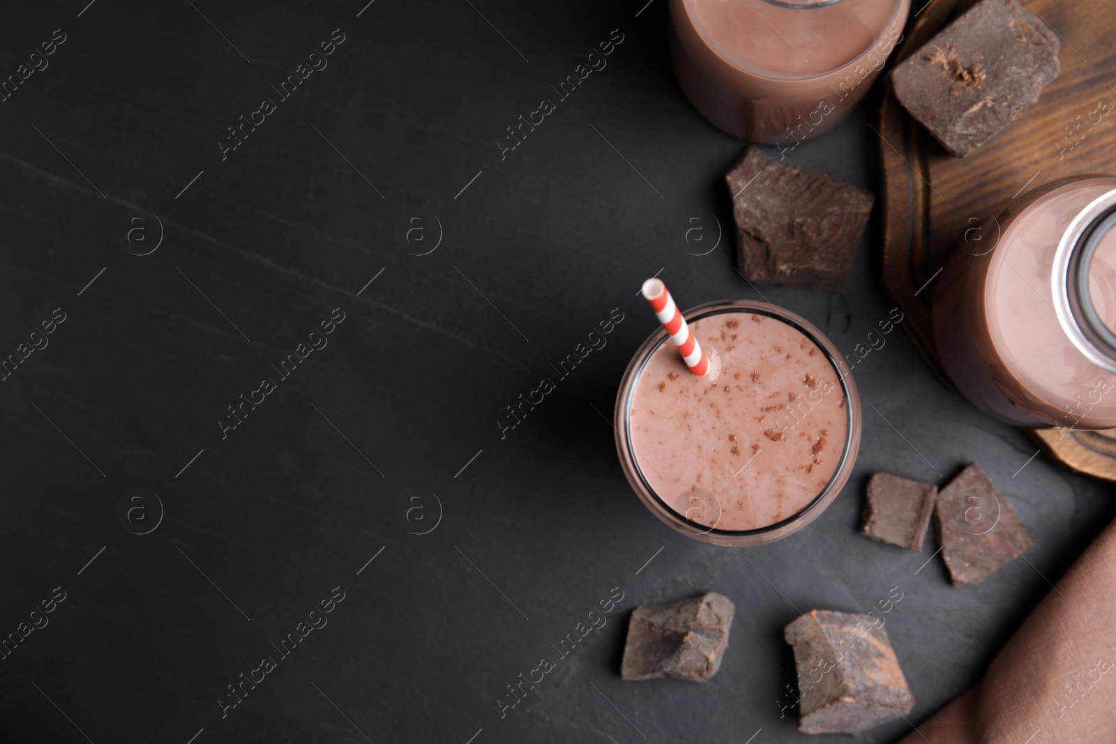 Photo of Delicious chocolate milk on black table, flat lay. Space for text
