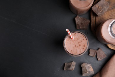 Photo of Delicious chocolate milk on black table, flat lay. Space for text