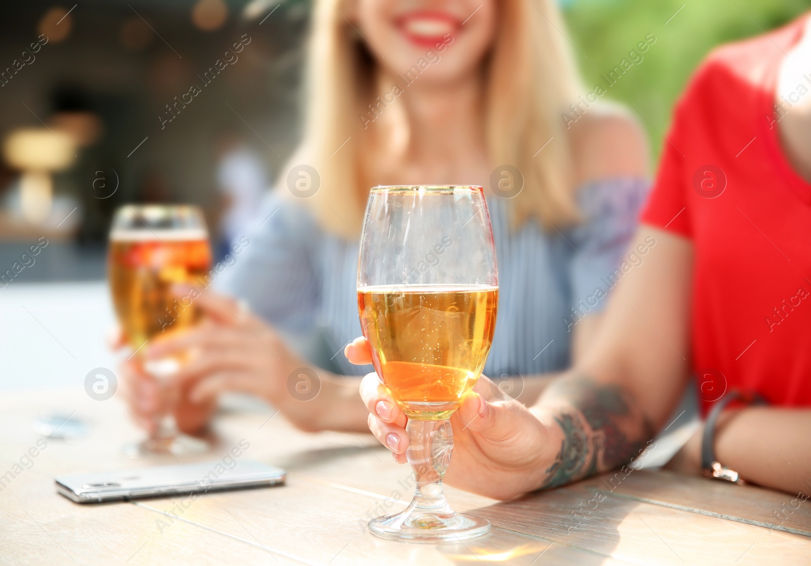 Photo of Young women with glasses of cold beer at table