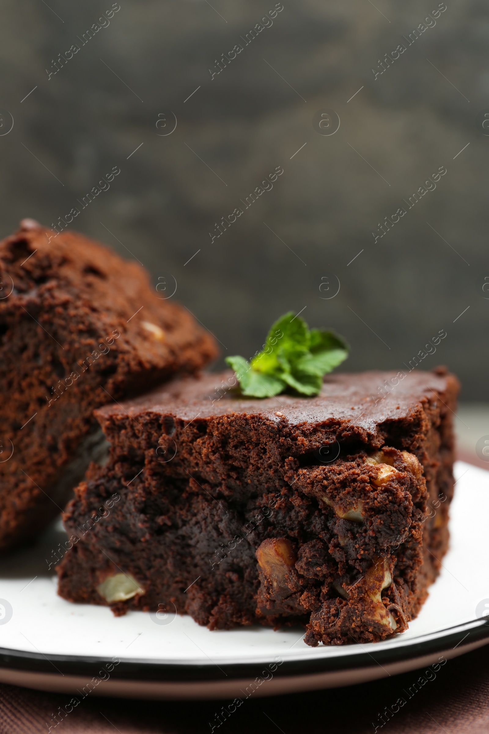 Photo of Delicious brownies with nuts and mint on table, closeup. Space for text