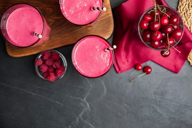 Tasty fresh milk shakes with berries on black table, flat lay. Space for text