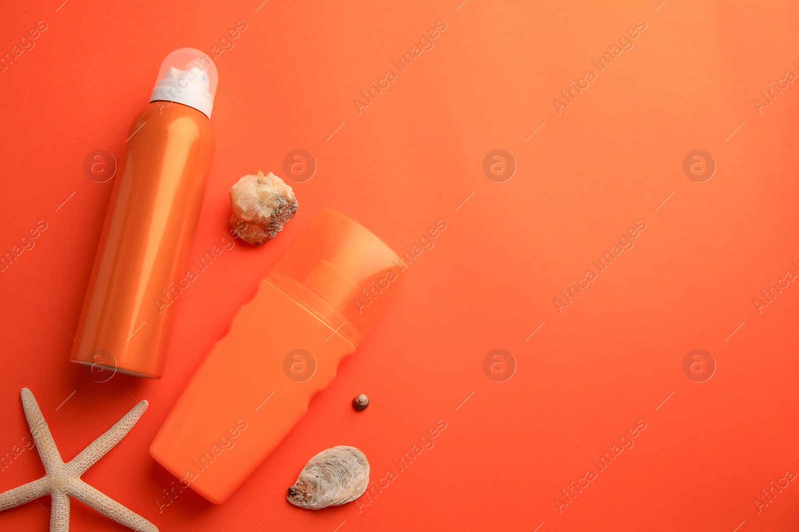 Photo of Bottles of sunscreen, seashells and starfish on coral background, flat lay. Space for text
