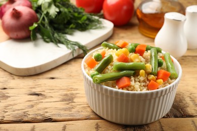 Photo of Delicious bulgur with vegetables on wooden table, closeup. Space for text