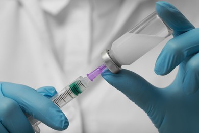 Photo of Doctor filling syringe with hepatitis vaccine from glass vial, closeup