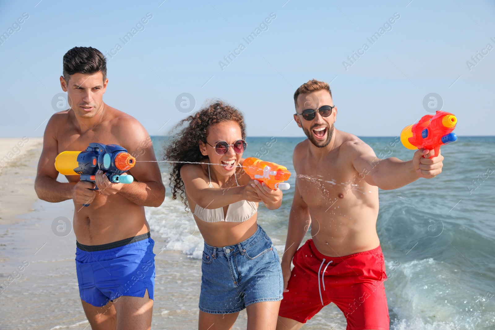 Photo of Friends with water guns having fun on beach