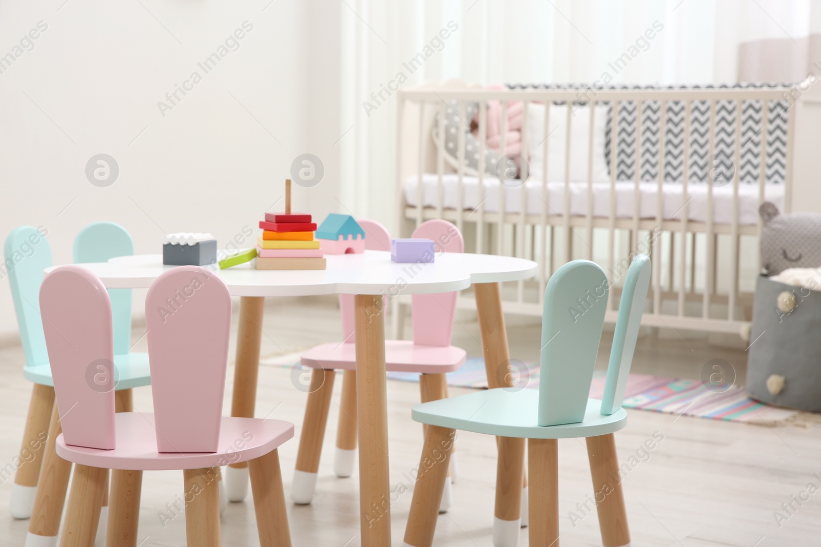 Photo of Cute baby room interior with cot and little table