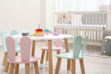 Photo of Cute baby room interior with cot and little table