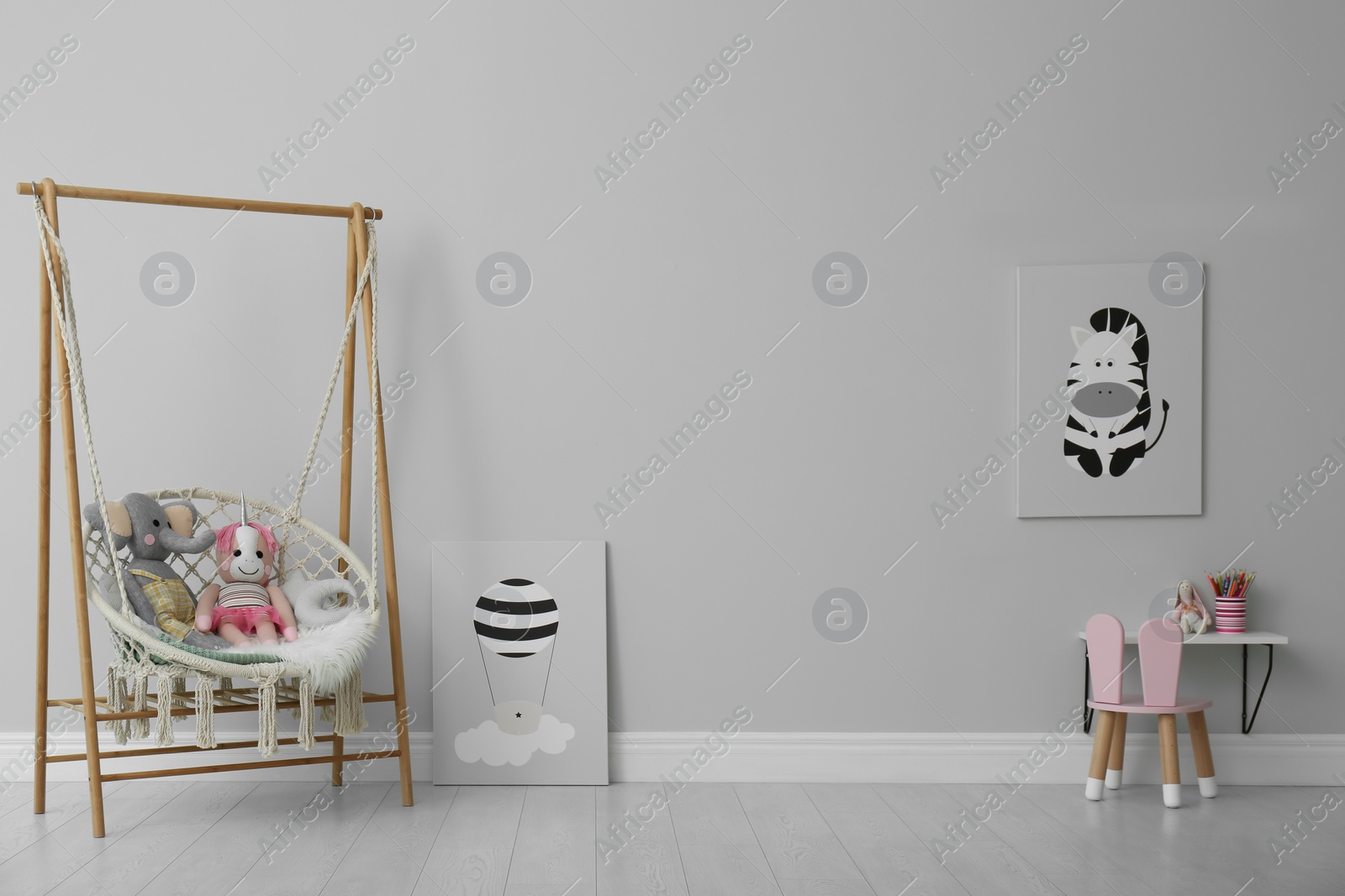 Photo of Stylish child's room interior with adorable paintings and hanging chair