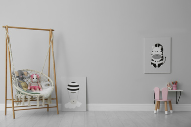 Photo of Stylish child's room interior with adorable paintings and hanging chair