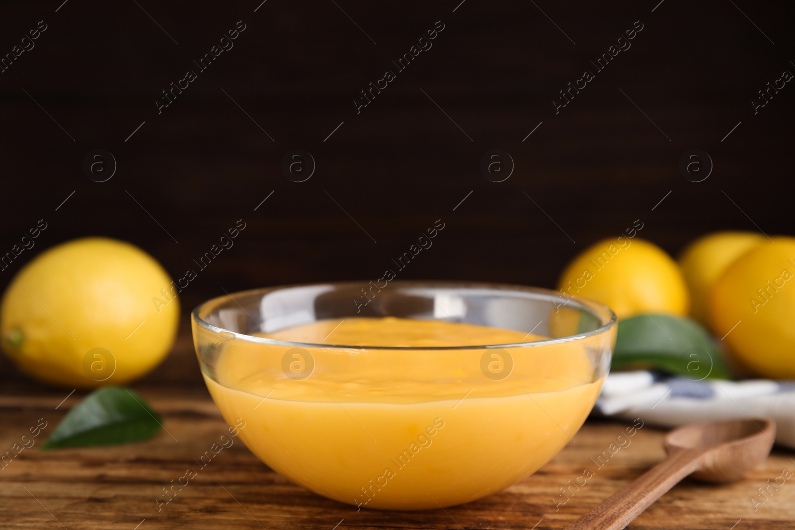 Photo of Delicious lemon curd in glass bowl on wooden table