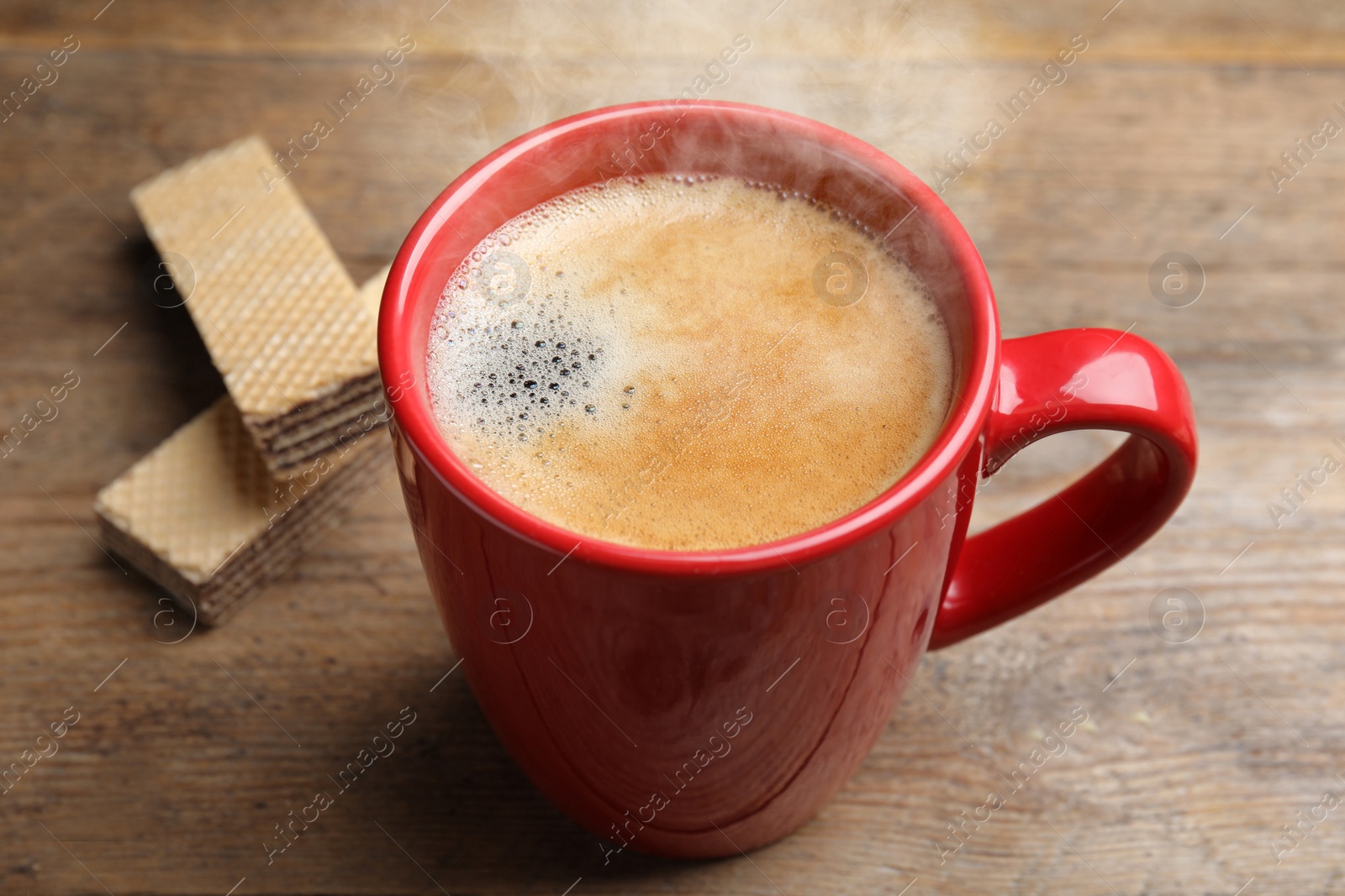 Photo of Delicious coffee and wafers for breakfast on wooden table