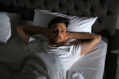 Man suffering from insomnia in bed at home