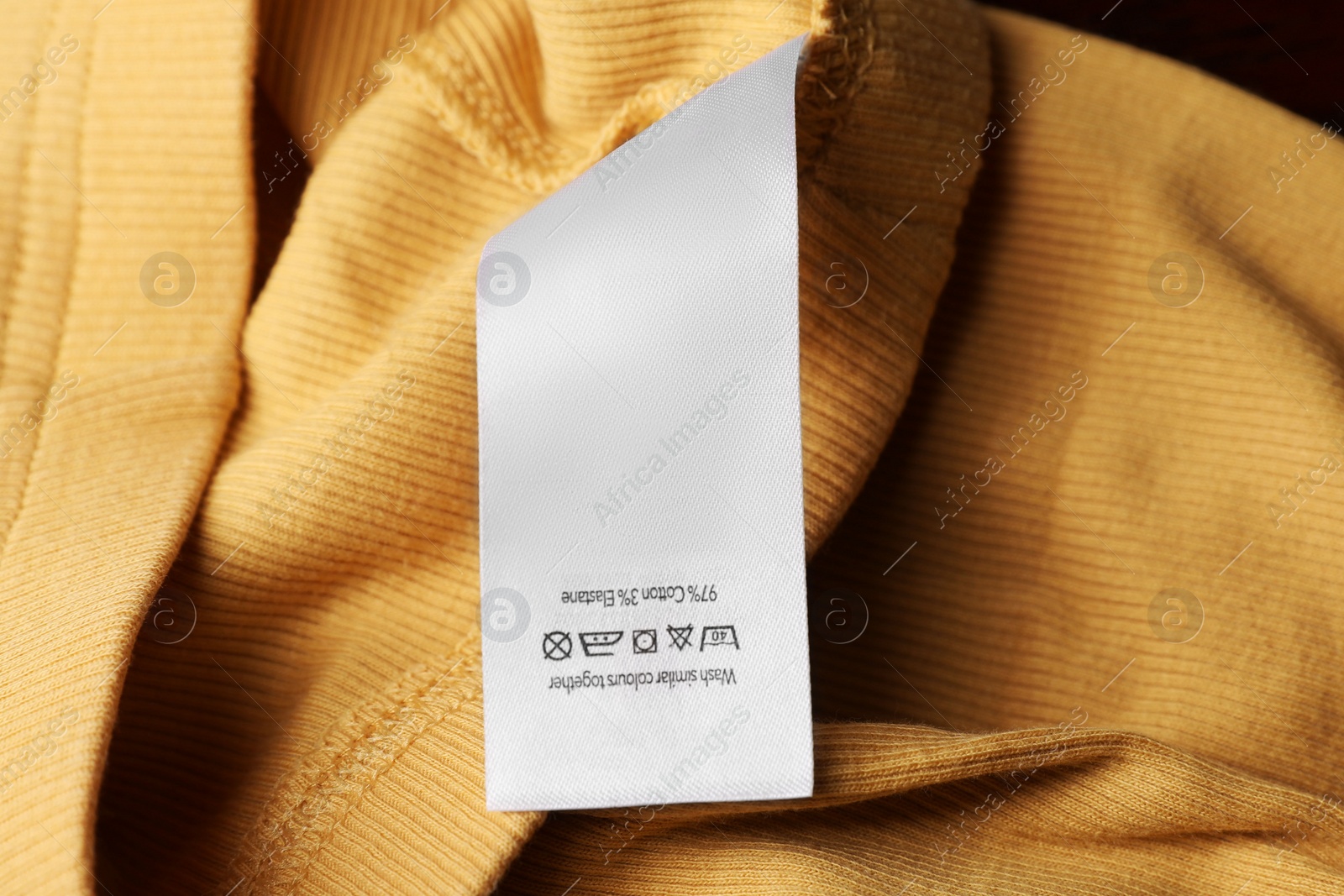 Photo of Clothing label on yellow garment, top view