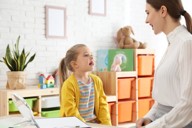 Speech therapist working with little girl in office