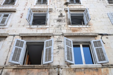 Old residential building with windows and wooden shutters, low angle view