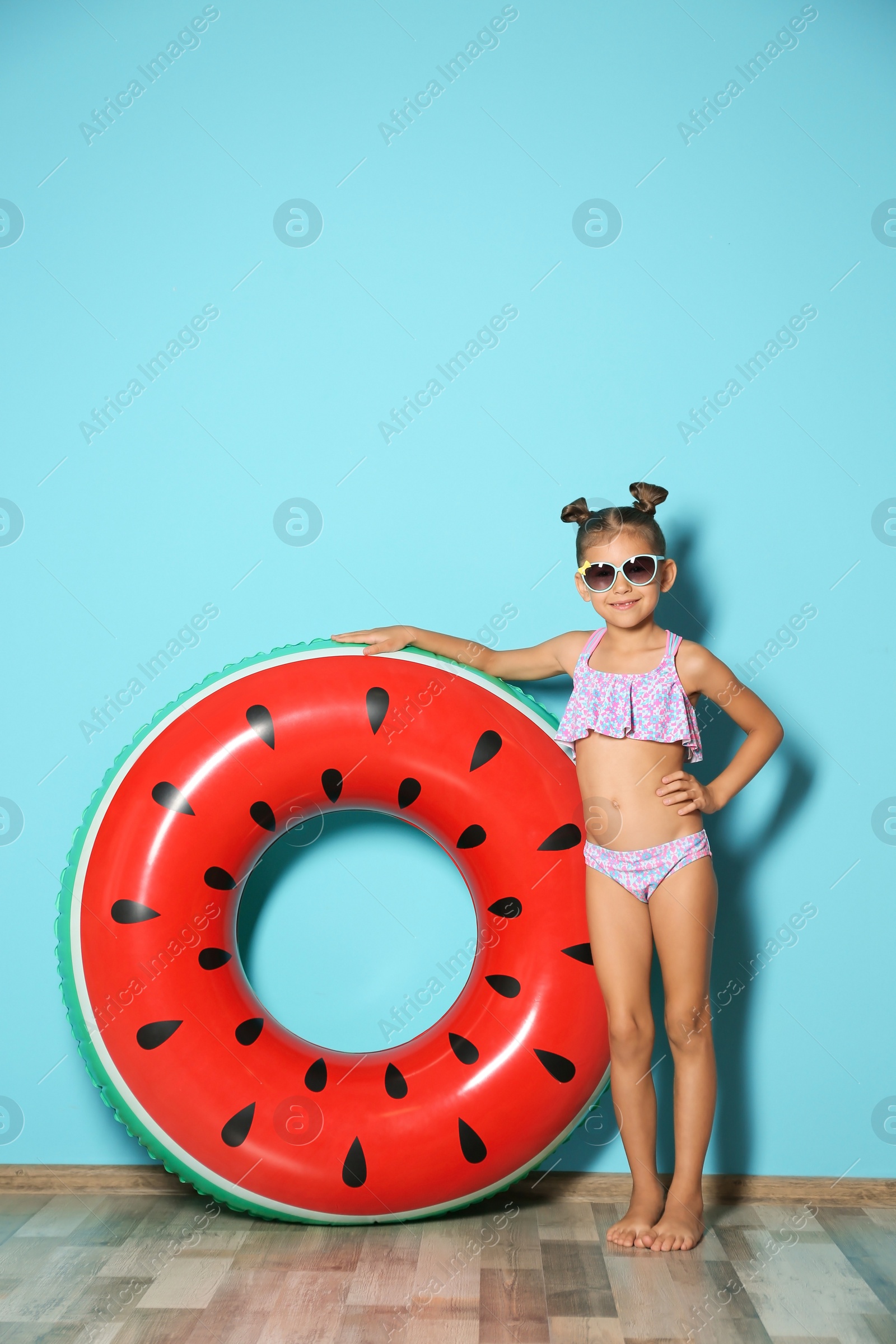 Photo of Cute little girl with inflatable ring near color wall