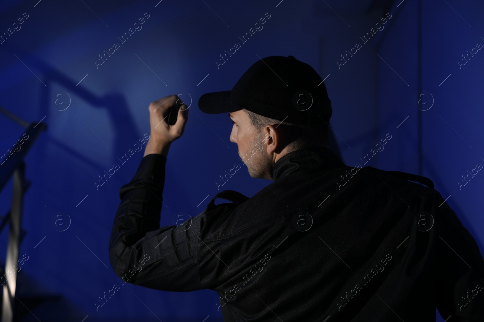 Photo of Male security guard with flashlight on stairs in darkness