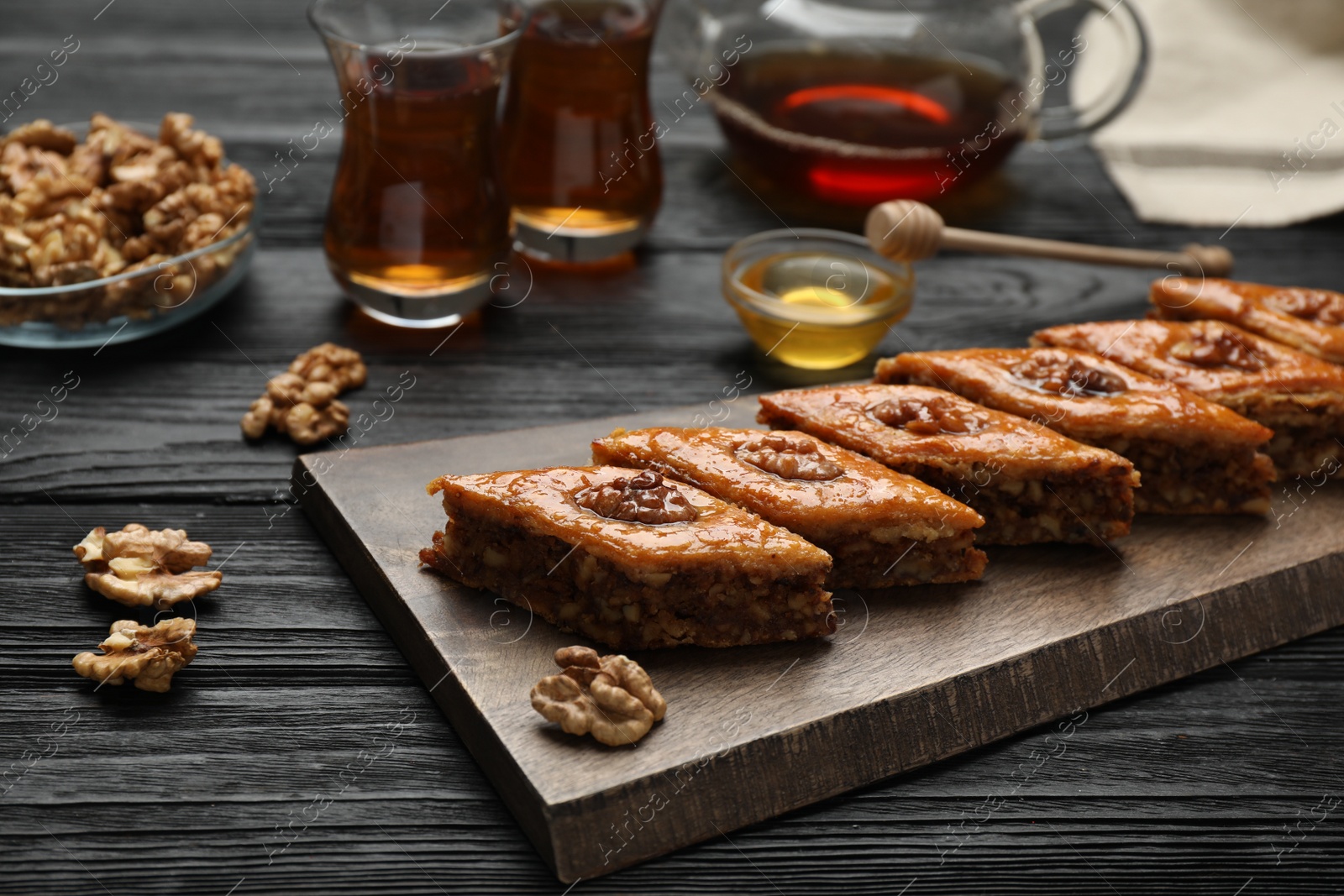 Photo of Delicious sweet baklava with walnuts on black wooden table