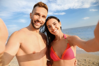 Photo of Happy young couple taking selfie on beach