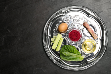 Passover Seder plate (keara) on black table, top view with space for text. Pesah celebration