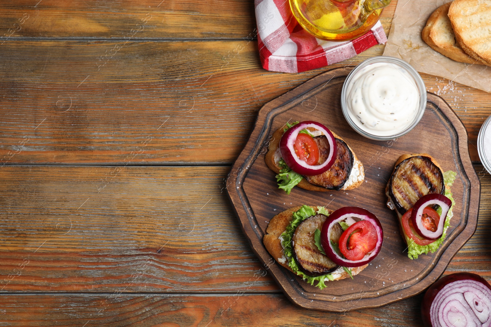 Photo of Delicious eggplant sandwiches served on wooden table, flat lay. Space for text