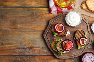 Photo of Delicious eggplant sandwiches served on wooden table, flat lay. Space for text