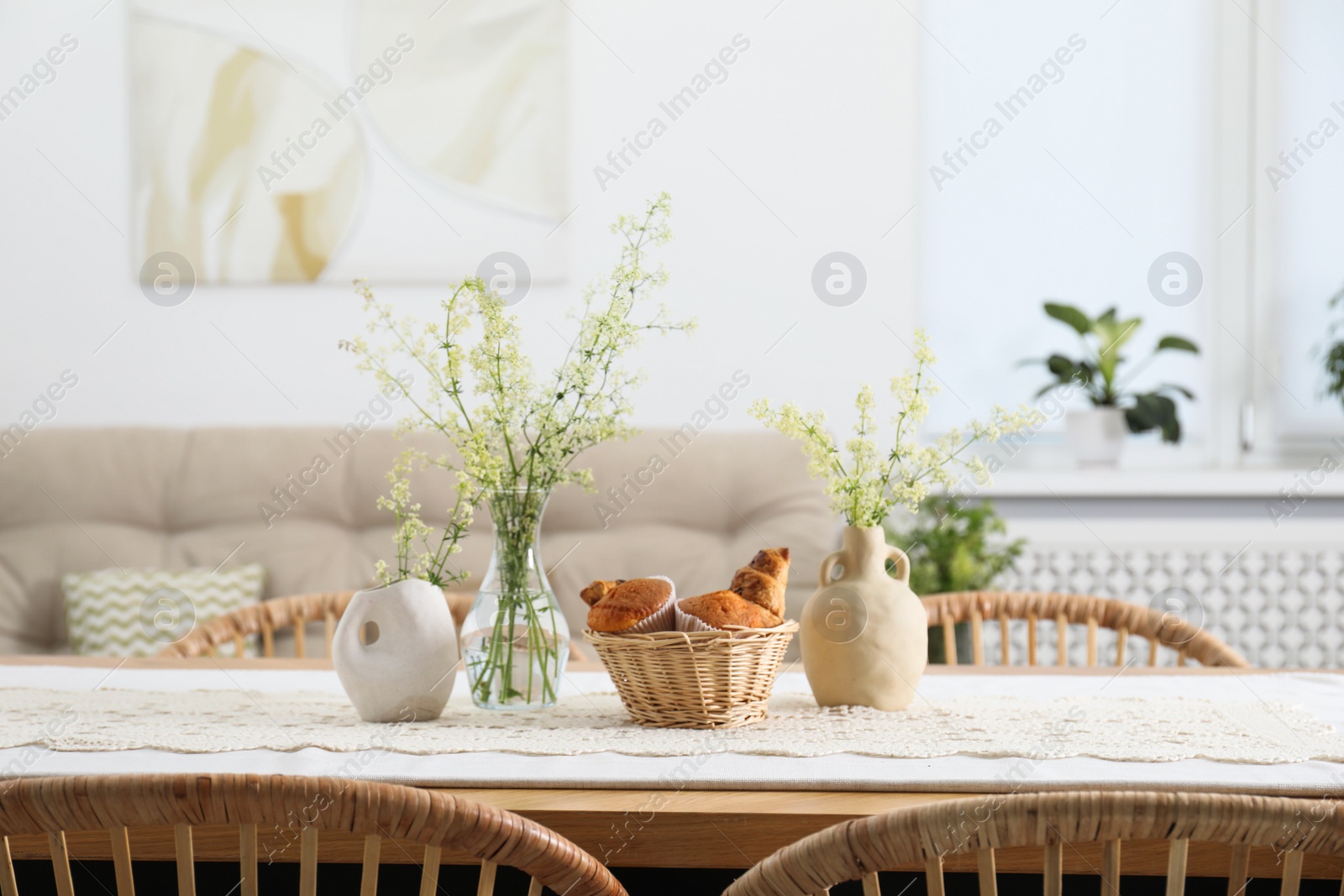 Photo of Fresh pastries and beautiful flowers on table in stylish dining room