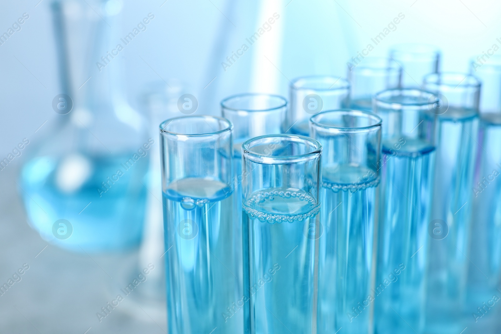 Photo of Test tubes with liquid on blurred background, closeup with space for text. Solution chemistry