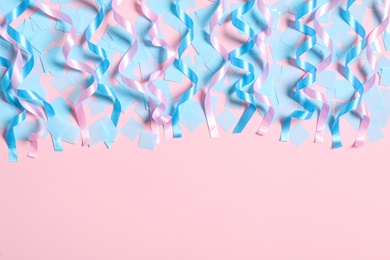 Photo of Shiny serpentine streamers and blue confetti on pink background, flat lay. Space for text