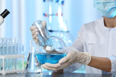 Doctor holding Florence flask with blue liquid, closeup. Laboratory analysis