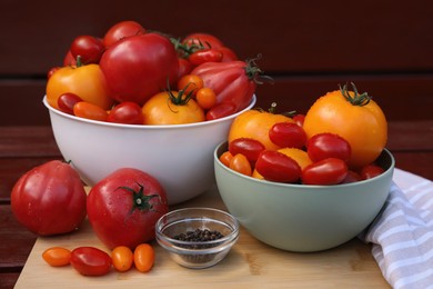 Photo of Bowls with fresh tomatoes and spices on wooden surface