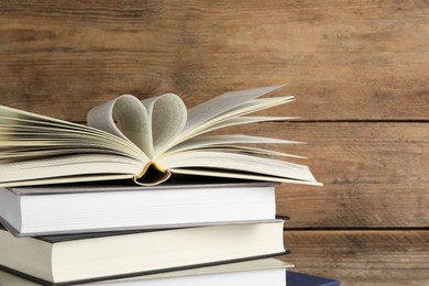 Stack of hardcover books on wooden table, space for text