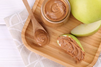 Fresh green apples with peanut butter on white wooden table, top view