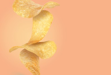 Stack of tasty potato chips on pale coral background, space for text