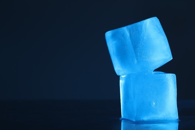Photo of Crystal clear ice cubes on dark background, space for text. Color tone effect