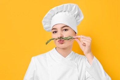 Photo of Professional chef with fresh rosemary having fun on yellow background