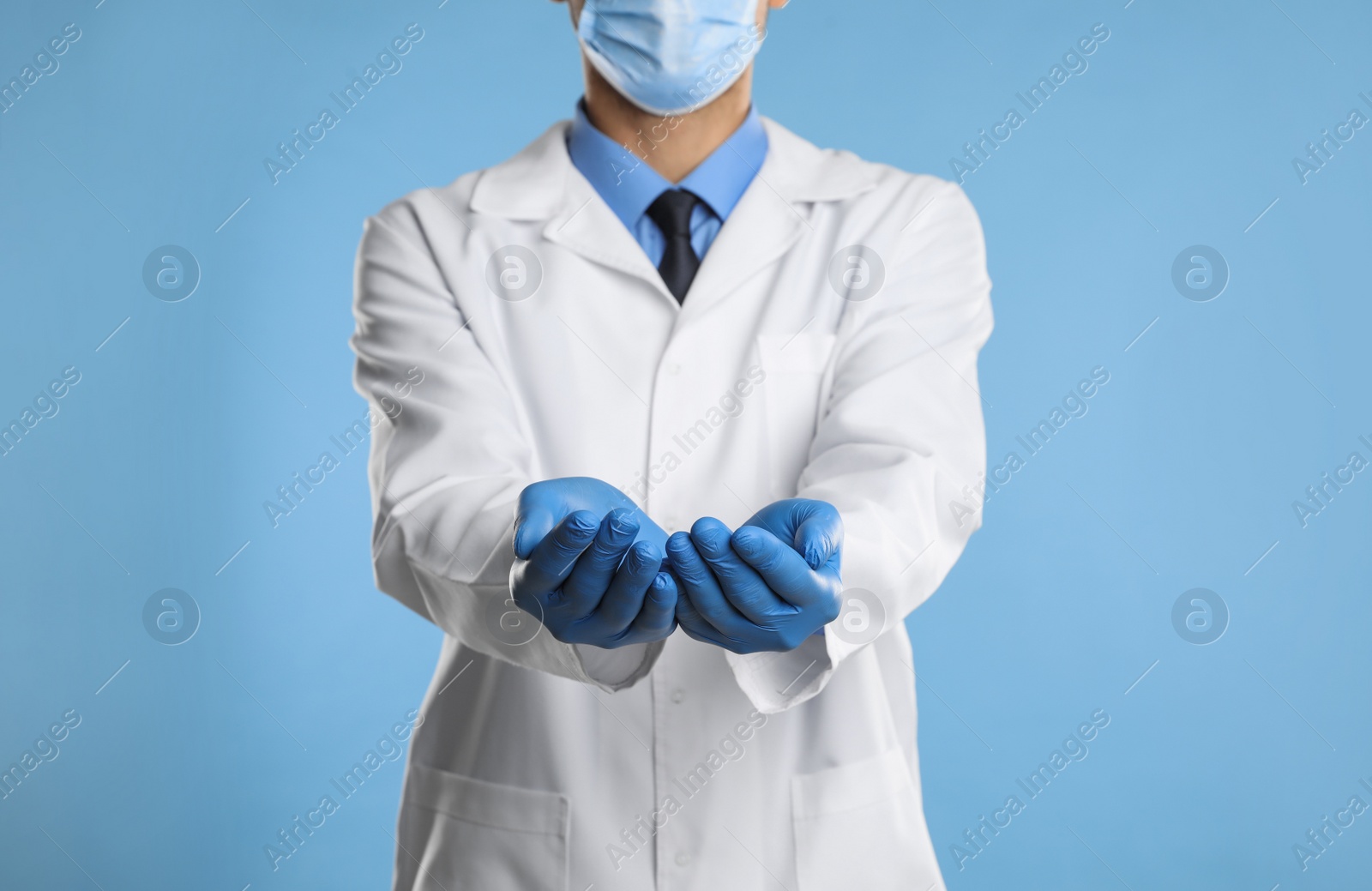 Photo of Dentist holding something on light blue background, closeup