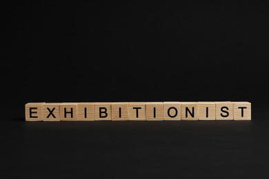 Photo of Word EXHIBITIONIST made with wooden cubes on black background