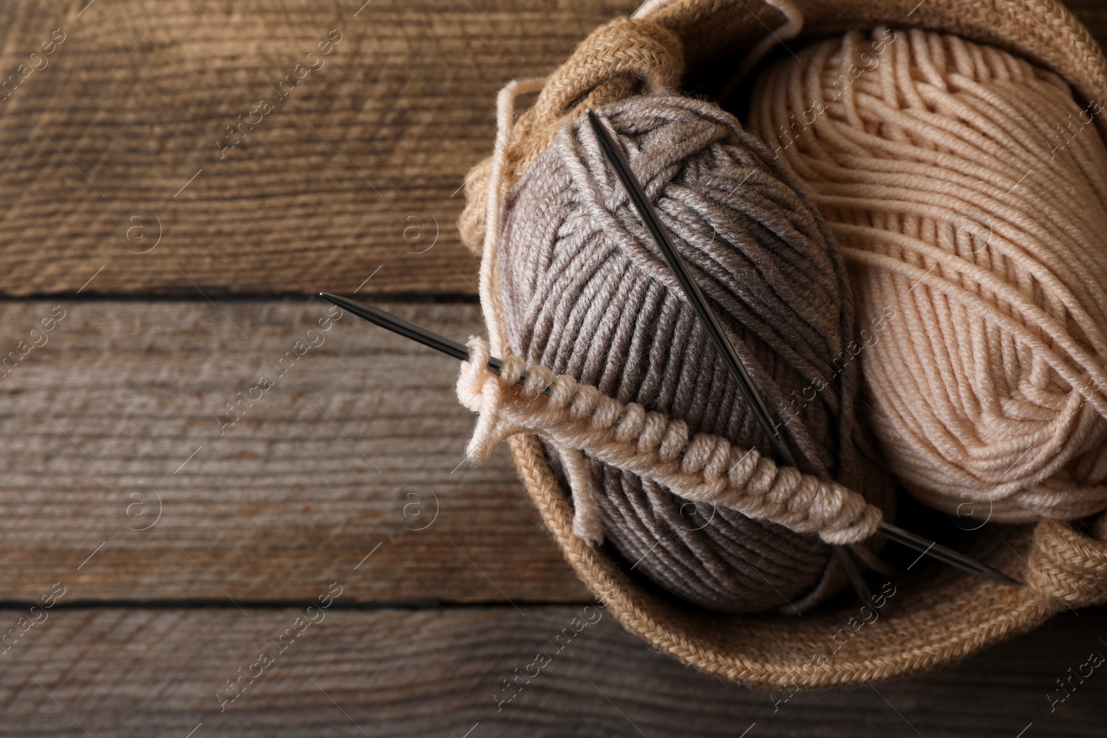 Photo of Soft colorful yarns, knitting and metal needles on wooden table, top view. Space for text