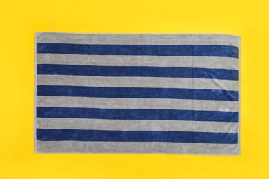 Photo of Striped beach towel on yellow background, top view