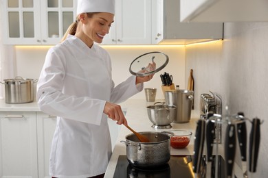 Photo of Professional chef cooking delicious dish in saucepan indoors