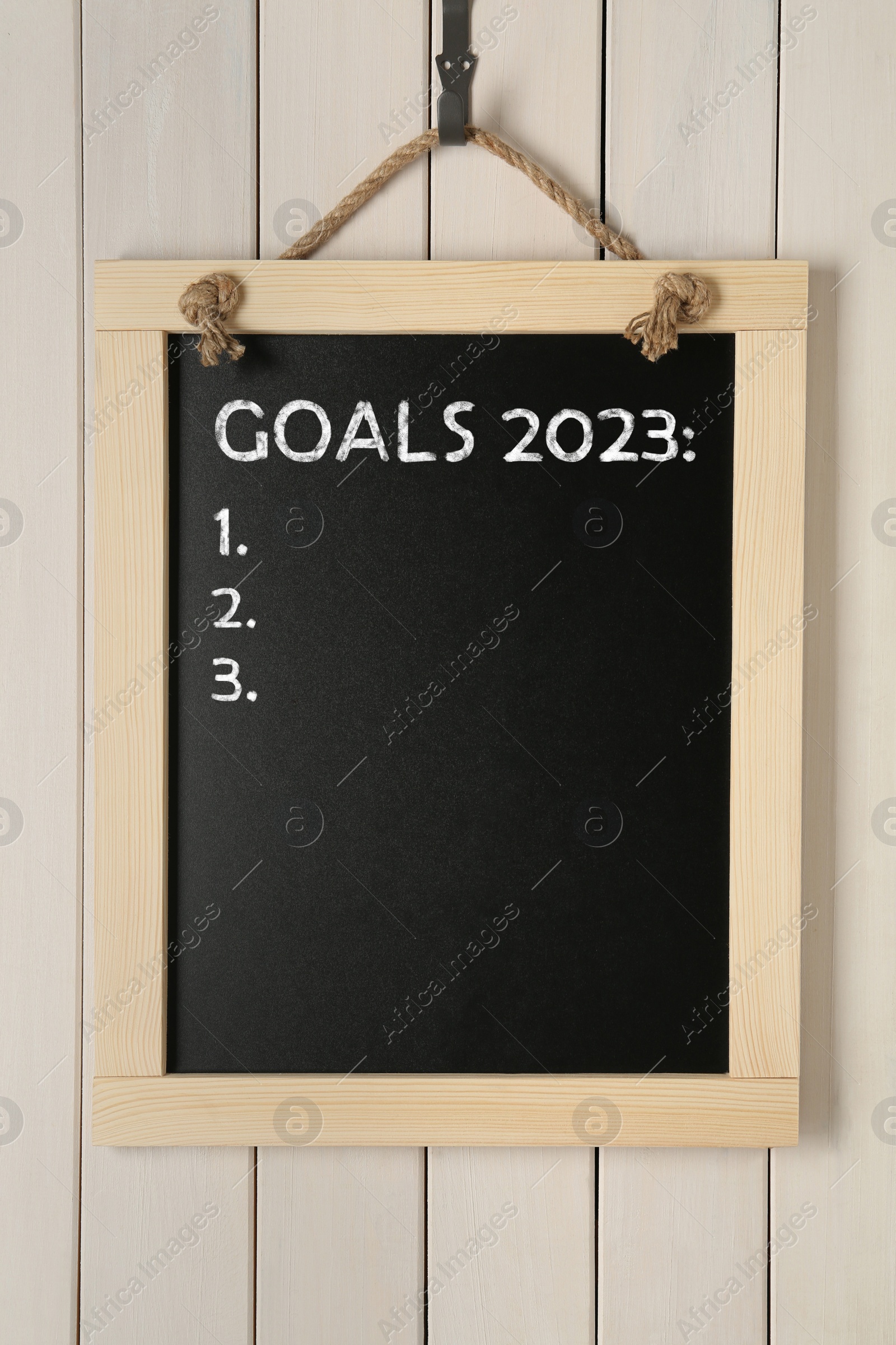 Image of Blackboard with phrase GOALS 2023 and empty checklist on hanging on white wooden background