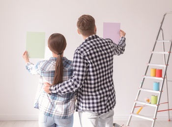 Young couple choosing color for wall indoors