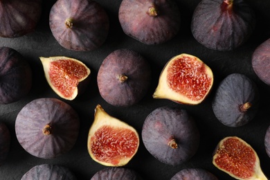 Photo of Tasty cut and whole figs on black table, flat lay