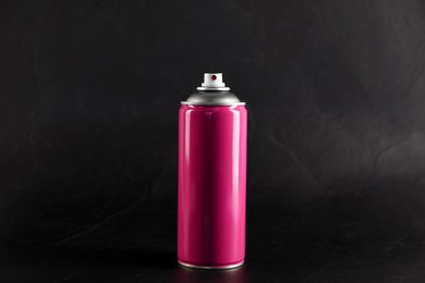 Photo of Pink can of spray paint on black background