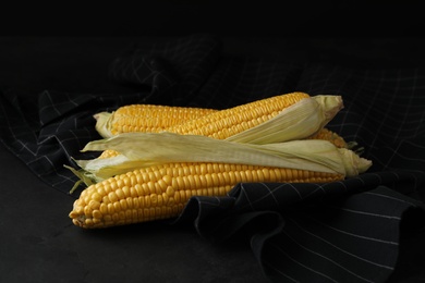 Photo of Ripe sweet corn cobs on black table