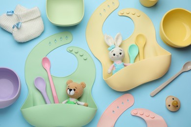 Photo of Flat lay composition with baby accessories and bibs on light blue background
